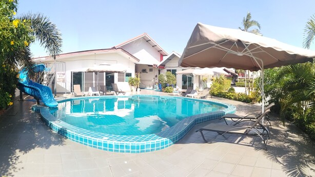 A swimming pool with a blue slide, surrounded by lounge chairs and umbrellas. - Baan Kaew Ruen Kwan (Pattaya)