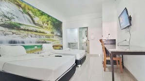 A hotel room with a large mural of a waterfall, two single beds, a desk with a chair, and a TV mounted on the wall. - Baan Kaew Ruen Kwan (Pattaya)