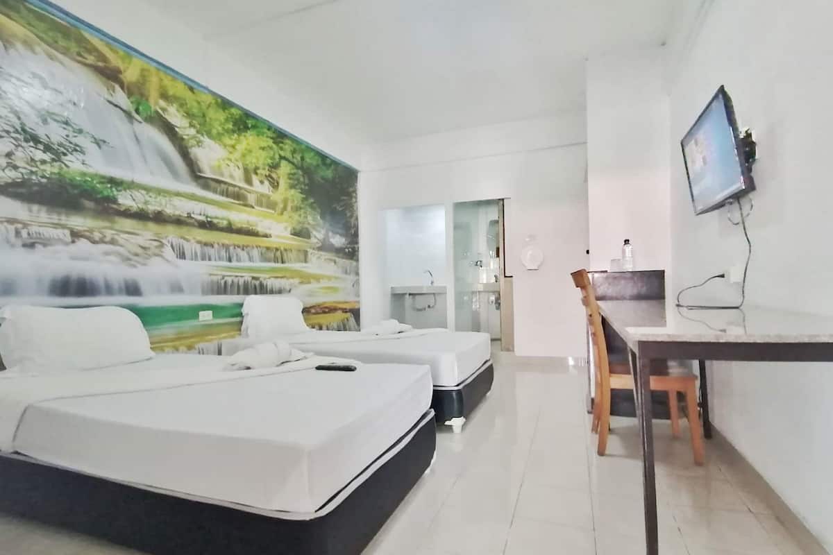 Une chambre d’hôtel avec une grande fresque représentant une cascade, deux lits simples, un bureau avec une chaise et un téléviseur fixé au mur.