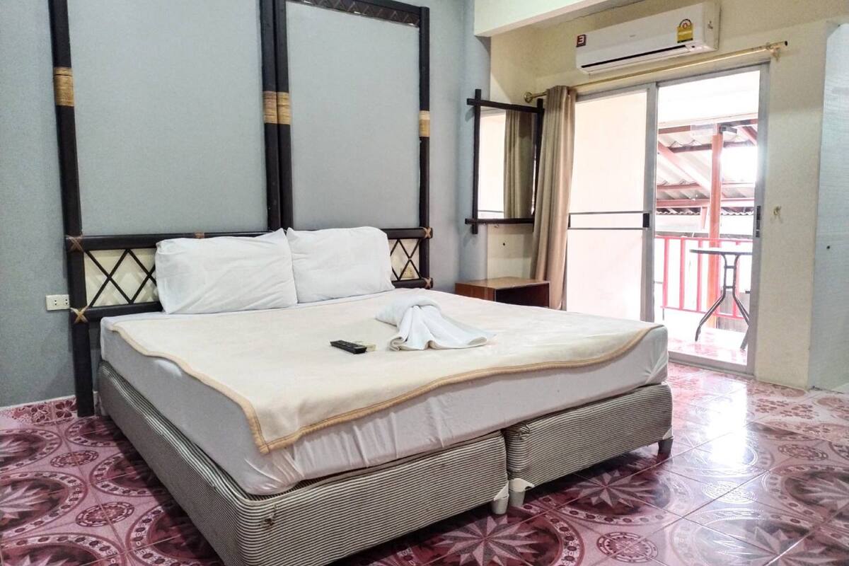 Une chambre d’hôtel équipée d’un lit, d’une petite table, d’un miroir et d’un appareil de climatisation.