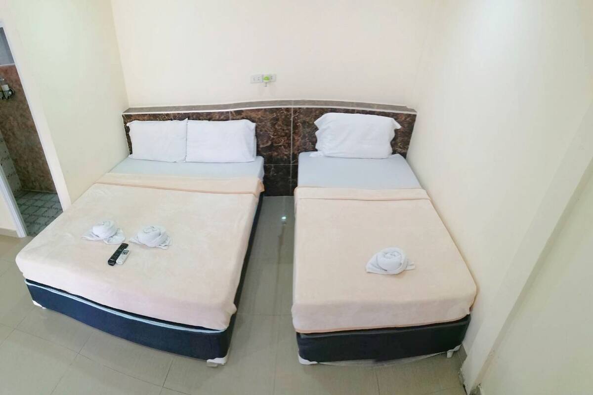Une chambre d’hôtel avec deux lits simples, chacun étant équipé d’un oreiller et d’une serviette.