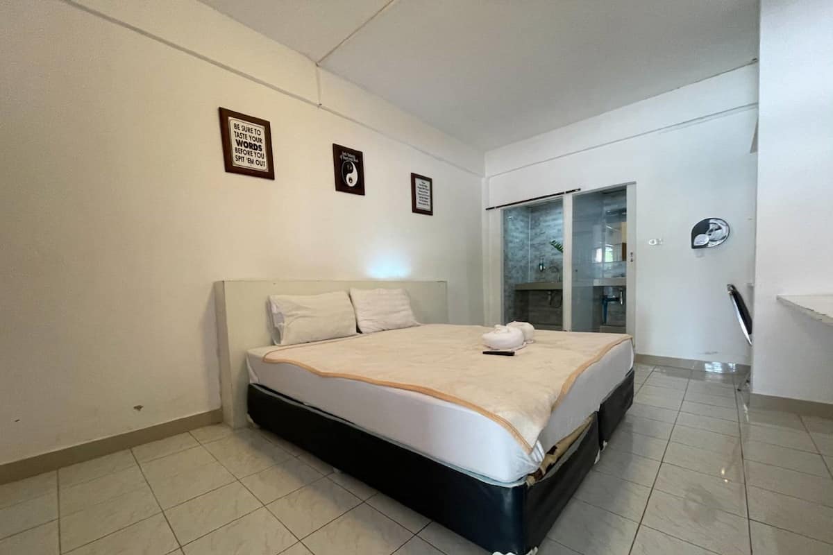 Une chambre d’hôtel avec un lit, une salle de bain dotée d’une porte en verre et une petite kitchenette.