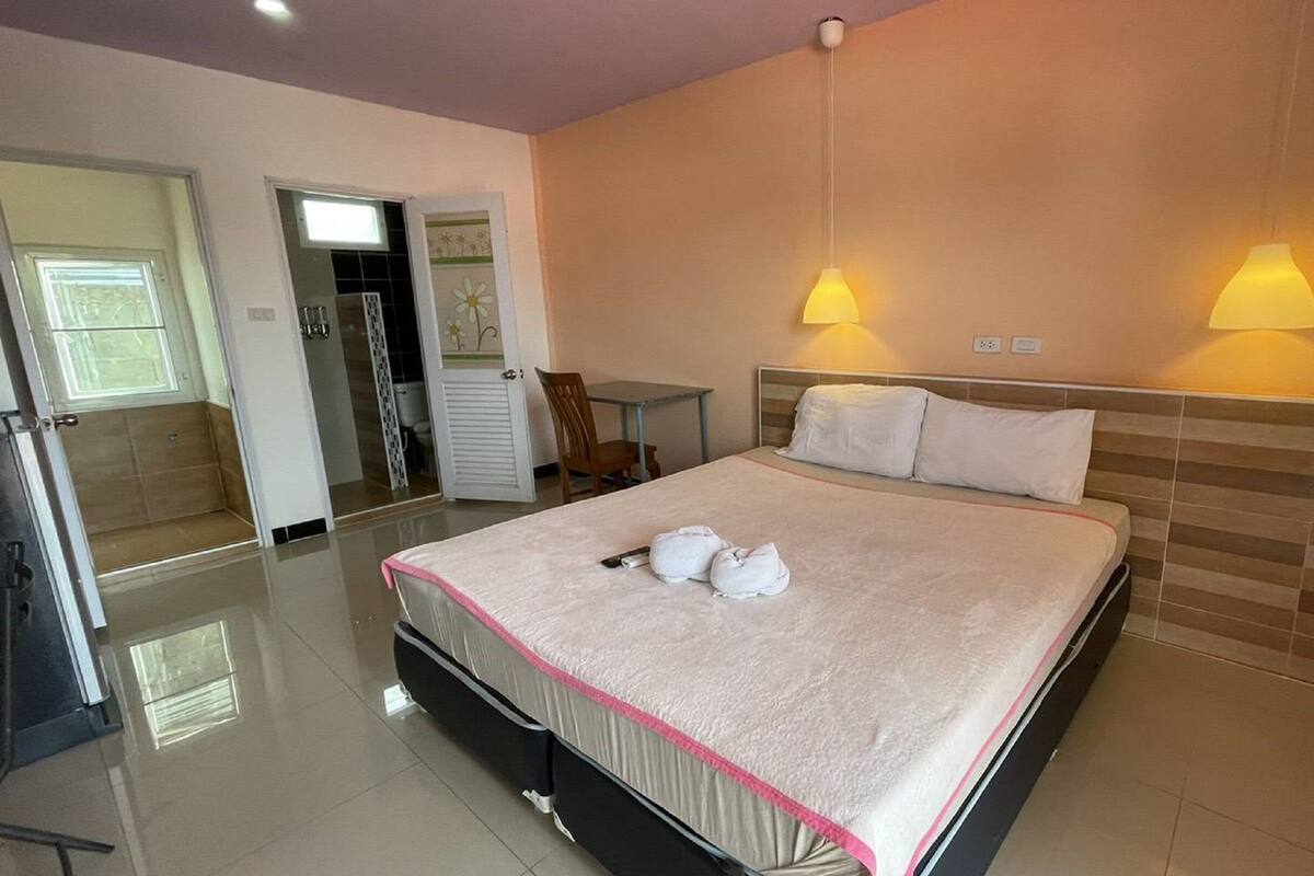 Une chambre d’hôtel avec un lit, des lampes de chevet, un bureau et une chaise.