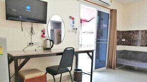 A compact hotel room with a desk, chair, and a television mounted on the wall. - Baan Kaew Ruen Kwan (Pattaya)