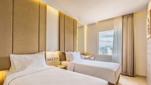 A hotel room with two beds, a large window, and a view of the city.