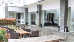 A spacious outdoor area with seating arrangements, large windows, and a modern architectural design.