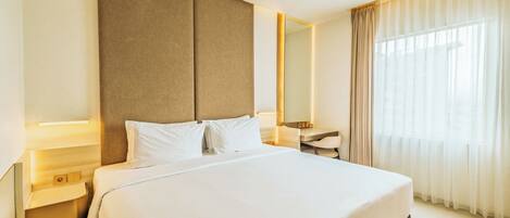 A hotel room with a large bed, bedside tables, a desk, and a mirror.