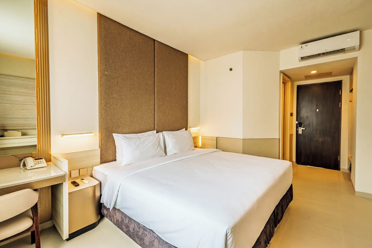 Habitación de hotel con una cama grande, una mesita de noche con teléfono y un escritorio con lámpara.