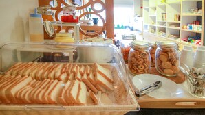 Un bufé con pan en rodajas, frascos de galletas y salsas.