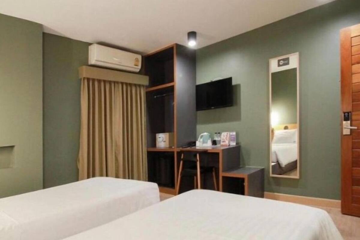 A hotel room with two beds, a desk, a TV, and a mirror.