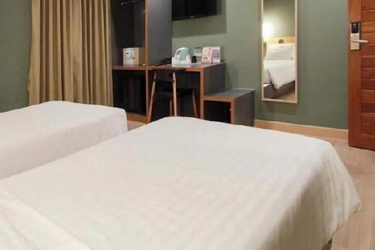 A hotel room with two beds, a desk, a TV, and a mirror.