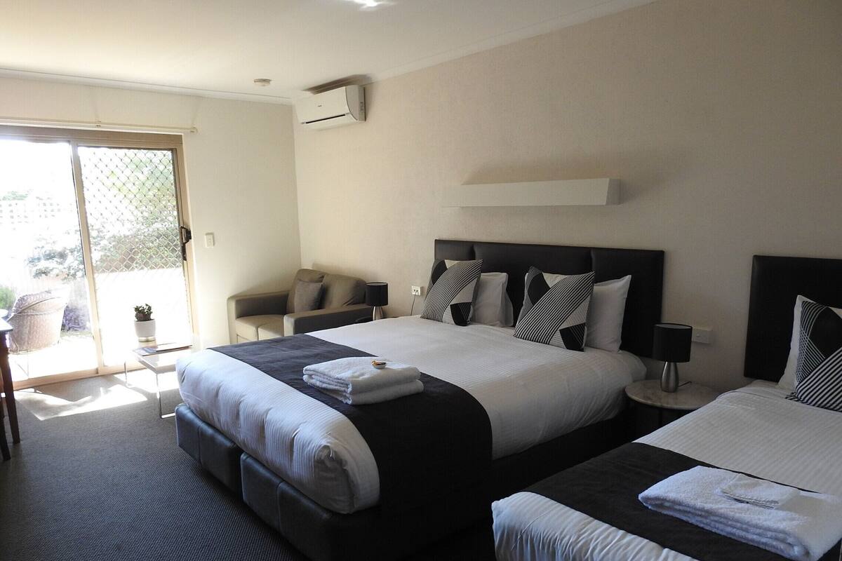 A hotel room with two beds, a sofa, a small table, and a chair.