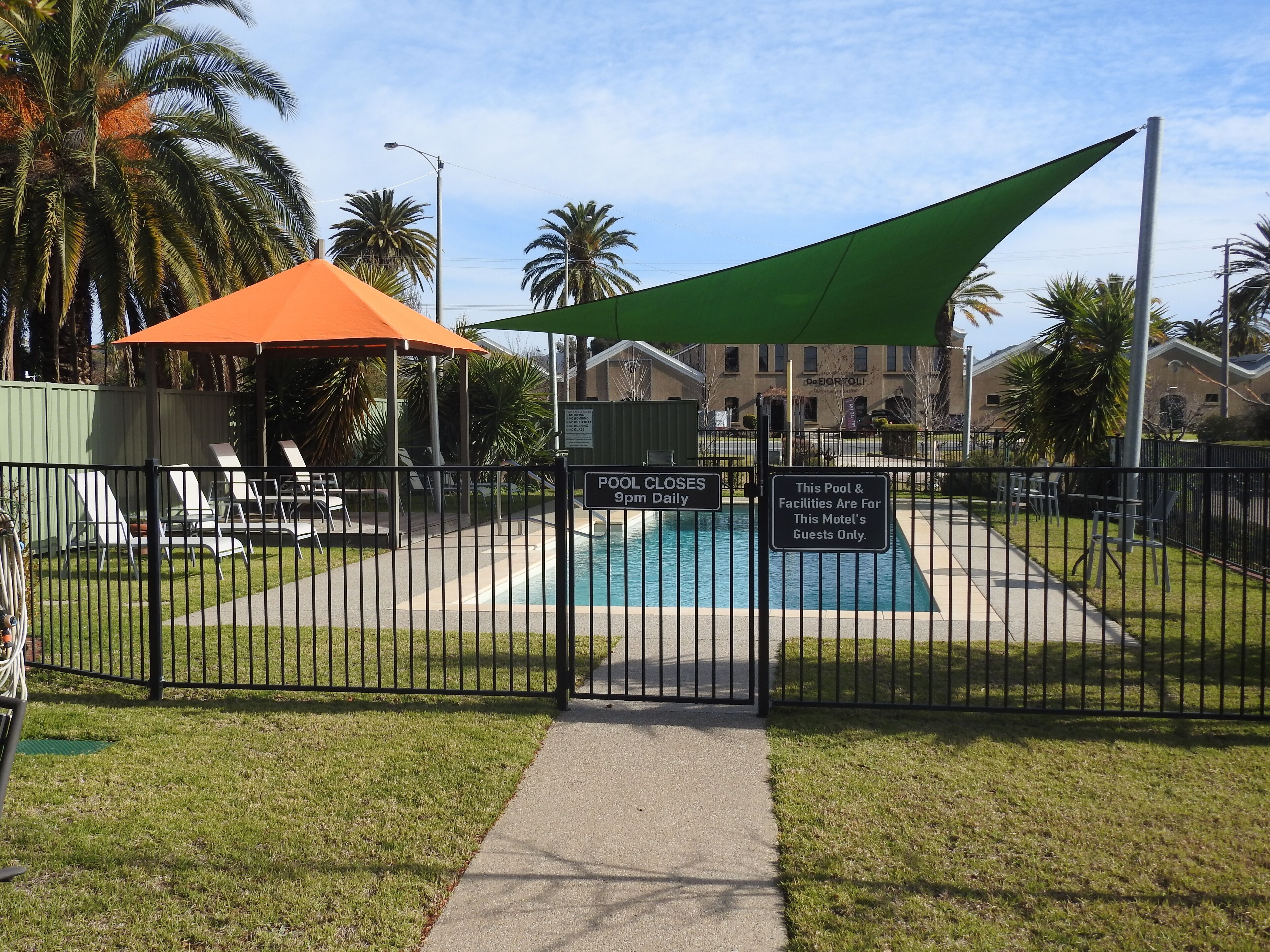 A fenced pool area with a sign indicating it closes at 9pm daily.