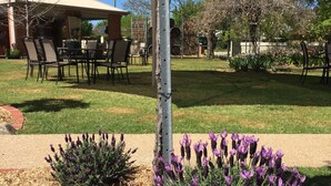 A patio area with outdoor seating, a pergola, and lavender plants. - Wine Village Motor Inn (Rutherglen)