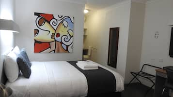 Ein Hotelzimmer mit einem Bett, einem Schreibtisch, einem Sessel, einem Spiegel und einem Bild an der Wand.