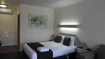 A hotel room with a bed, bedside tables, a lamp, a chair, and a painting on the wall.