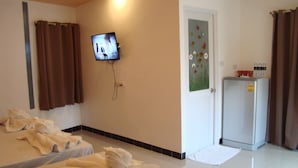 A hotel room with two beds, a television, a refrigerator, and a door with a floral decoration. - Hill Inn (Pattaya)