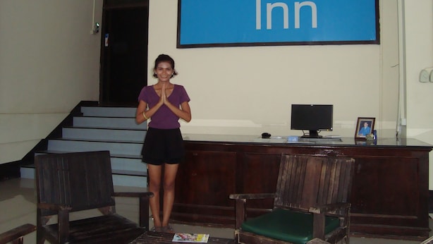 A person standing in front of a blue sign with "Hill Inn" written on it. - Hill Inn (Pattaya)