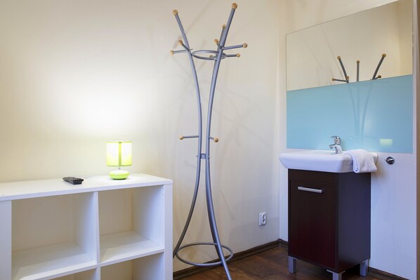 A bathroom with a white vanity, a mirror, and a floor lamp.