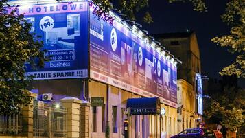 A hotel with a large illuminated sign advertising room rates and amenities.