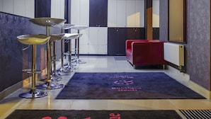 A hotel lobby with a modern design, featuring a reception desk, seating area, and a visible kitchenette. - Boutique Hostel (Lodz)
