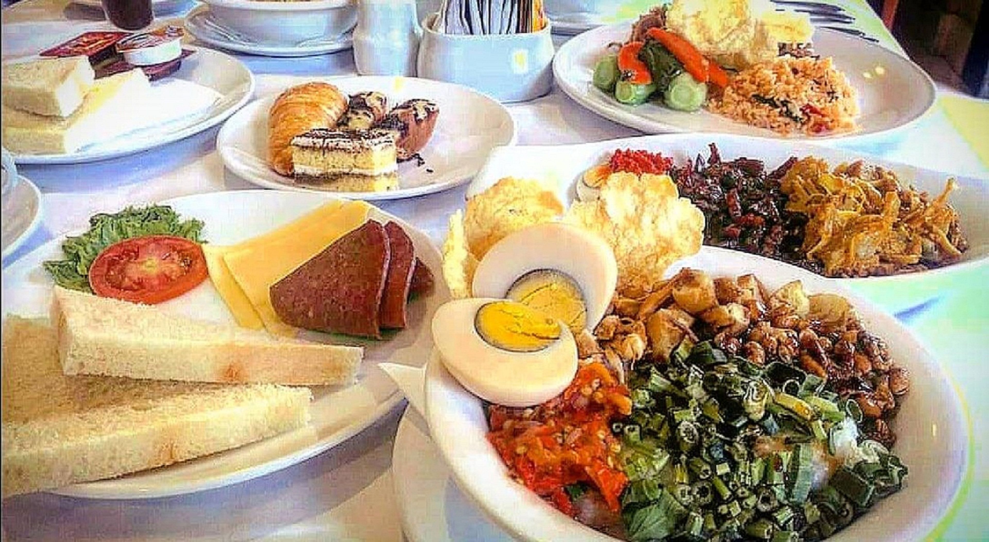 A table with various dishes including sandwiches, a salad, and a bowl of soup.
