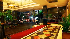 A hotel lobby with a red carpet, check-in counters, and a large chandelier. - Mega Anggrek Hotel & Convention (Jakarta)