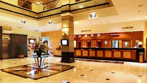 A hotel lobby with a reception desk, a cashier, a reception area, and a large decorative vase. - Mega Anggrek Hotel & Convention (Jakarta)
