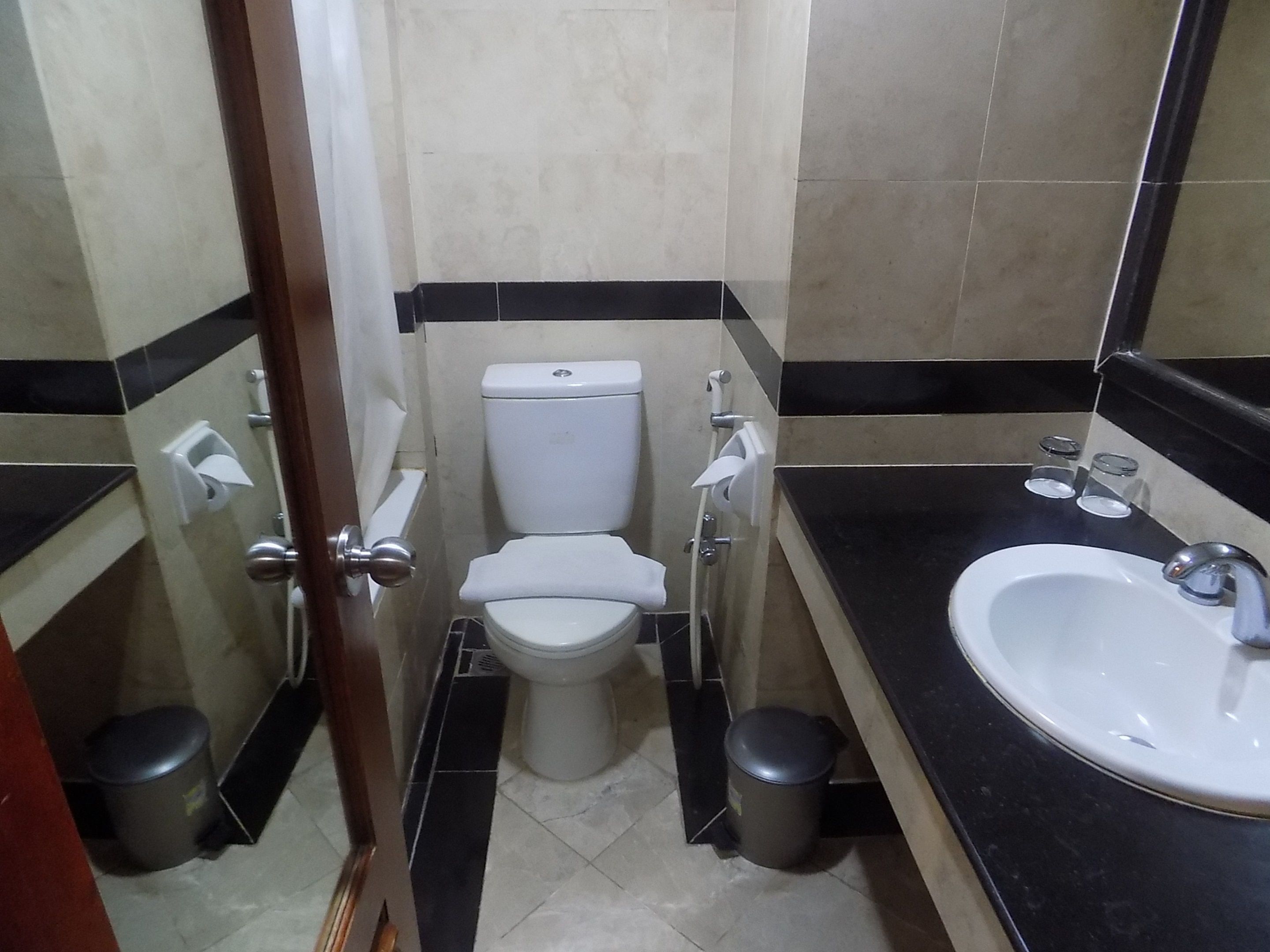 Un baño pequeño con inodoro, lavamanos y botes de basura.