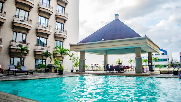 A hotel pool area with a covered seating area, multiple balconies, and potted plants. - Mega Anggrek Hotel & Convention (Jakarta)