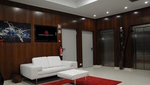 A modern lobby with a white sofa, a red and black rug, and two elevators. - Hotel Portas de Santa Rita (Valongo)