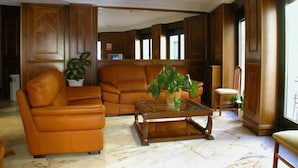 A living room with a leather sofa, a glass coffee table, and wooden paneling.