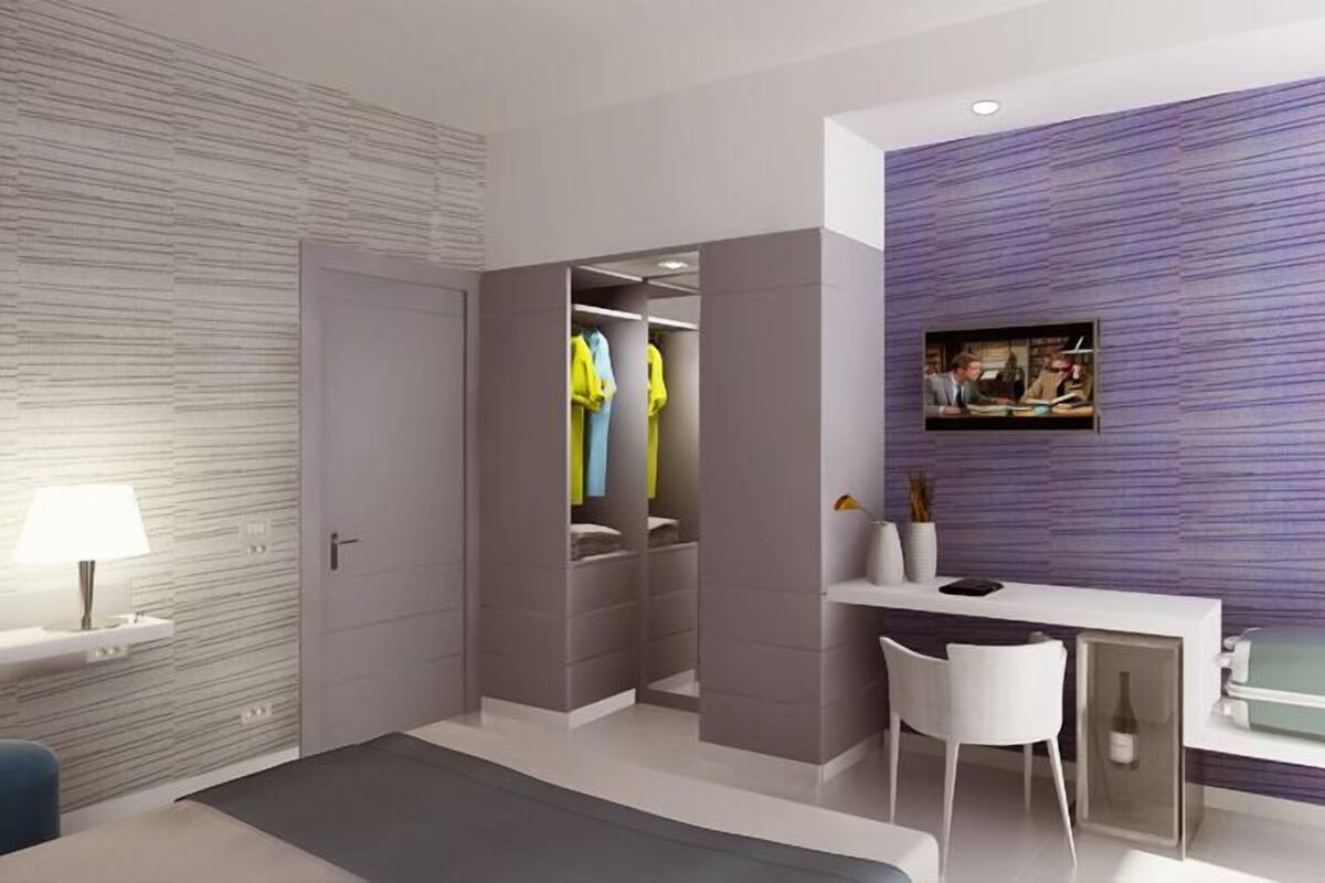 Une chambre moderne dotée d’un dressing, d’un bureau avec une chaise et d’un téléviseur fixé au mur.