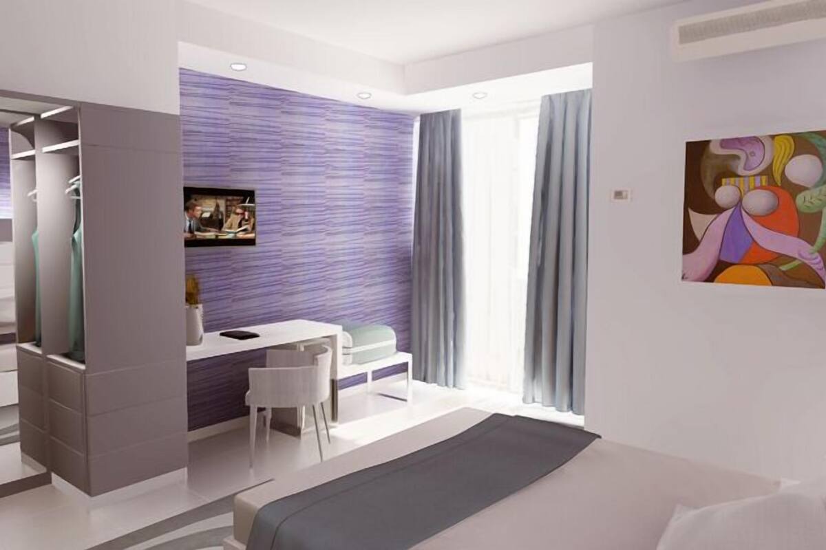 Une chambre d’hôtel moderne équipée d’un lit, d’un bureau, d’une chaise et d’une armoire.