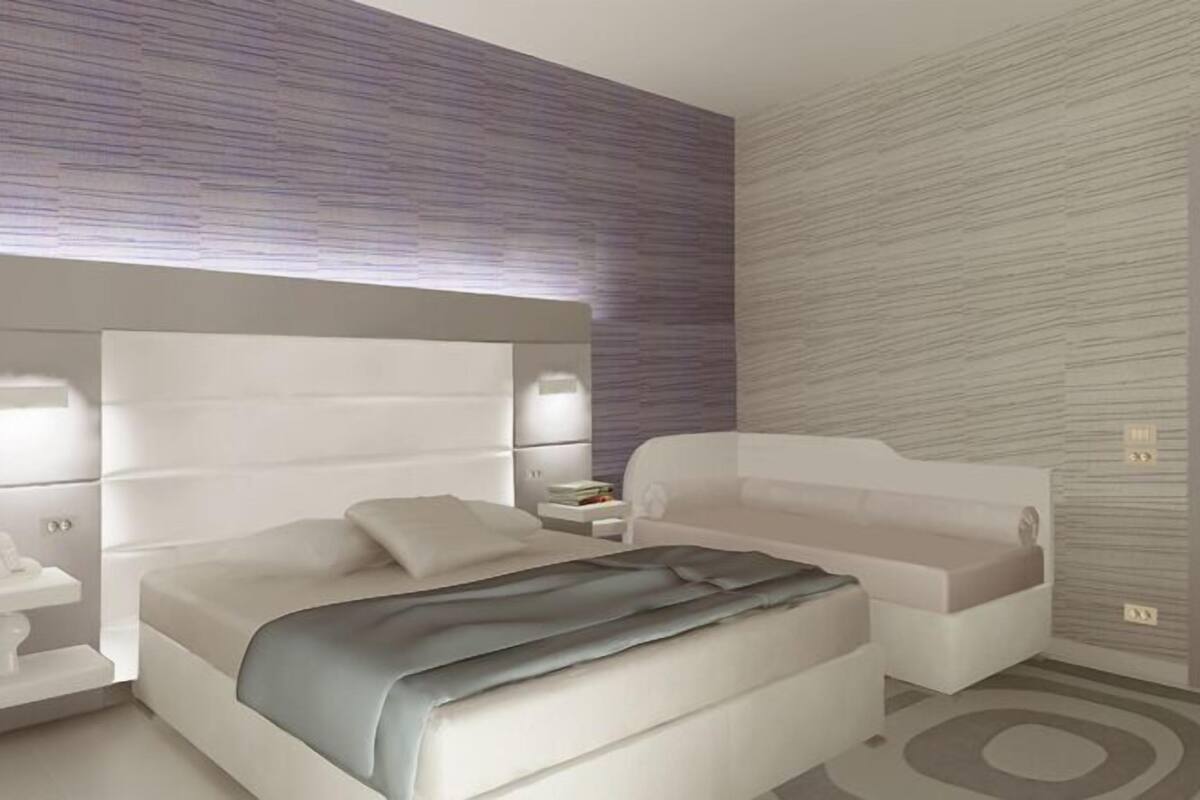 Une chambre à coucher moderne avec un grand lit, des tables de chevet et une petite table de nuit.