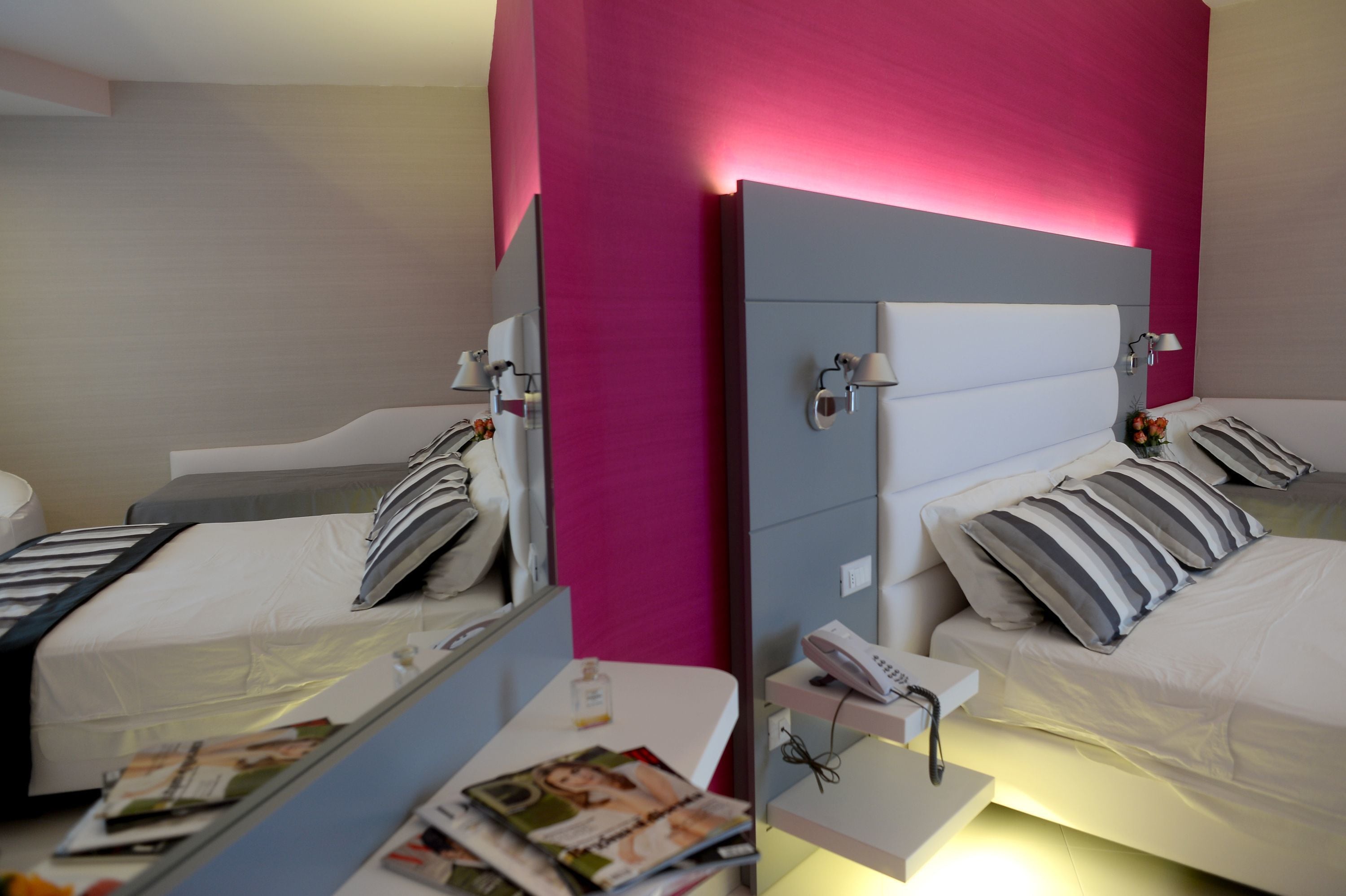 Ein Hotelzimmer mit zwei Betten, einem Nachttisch mit Lampe und einem Spiegel.
