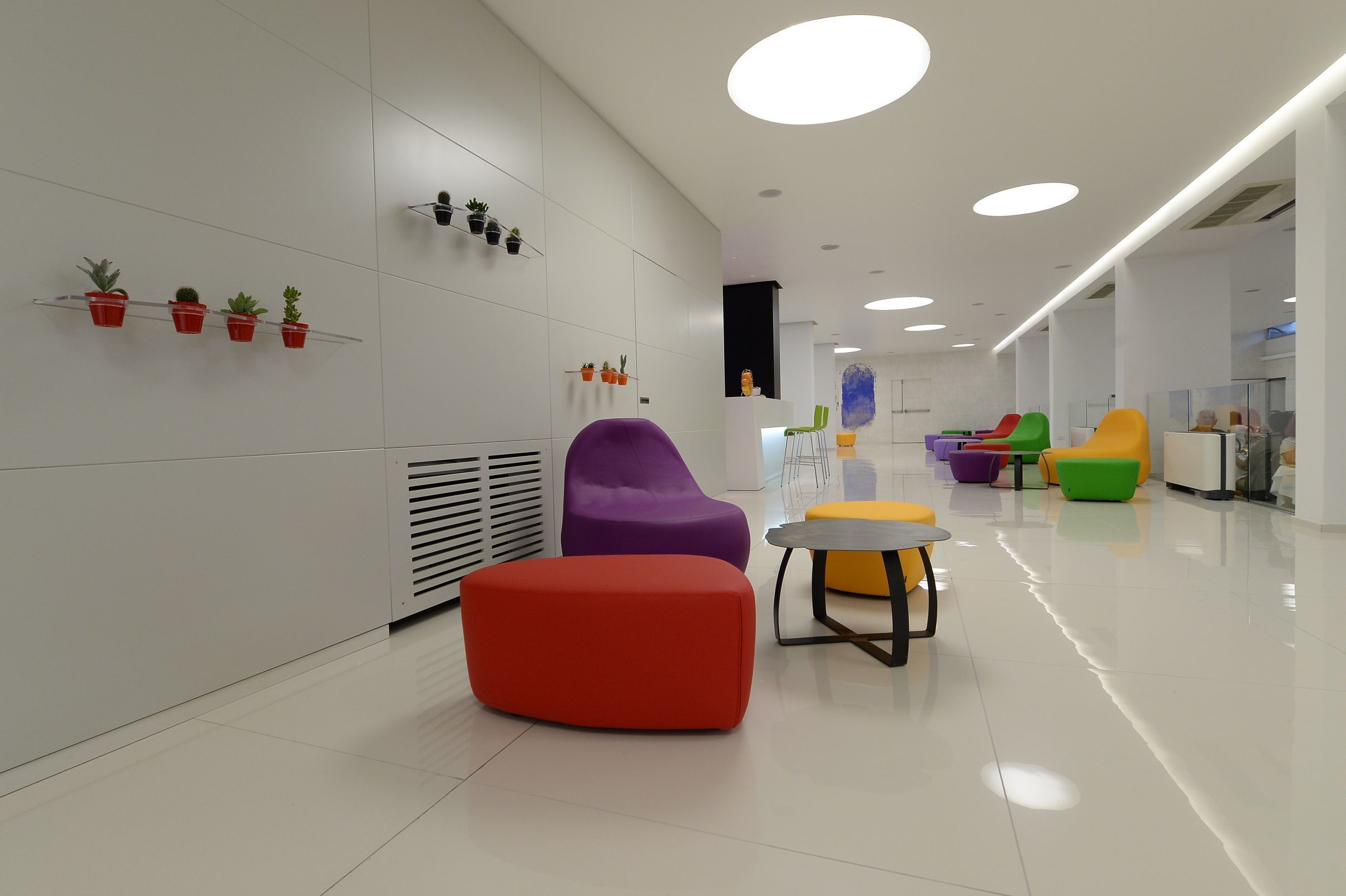 A modern interior with colorful seating, a white wall with potted plants, and a clean, well-lit space.
