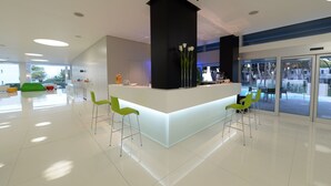 Un espace d’accueil moderne avec un comptoir de réception blanc, des chaises vertes et un pilier noir.