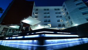 Un immeuble à plusieurs étages doté d’une architecture moderne, avec un escalier imposant dont les marches sont illuminées.