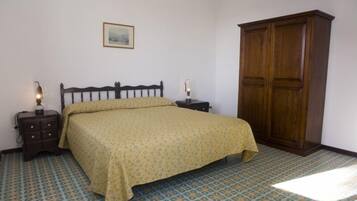 A bedroom with a bed, nightstands, a wardrobe, and patterned floor tiles.