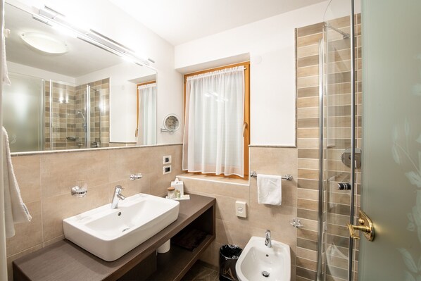 Un baño moderno con dos lavamanos, cabina de ducha de vidrio y tocador con espejo.