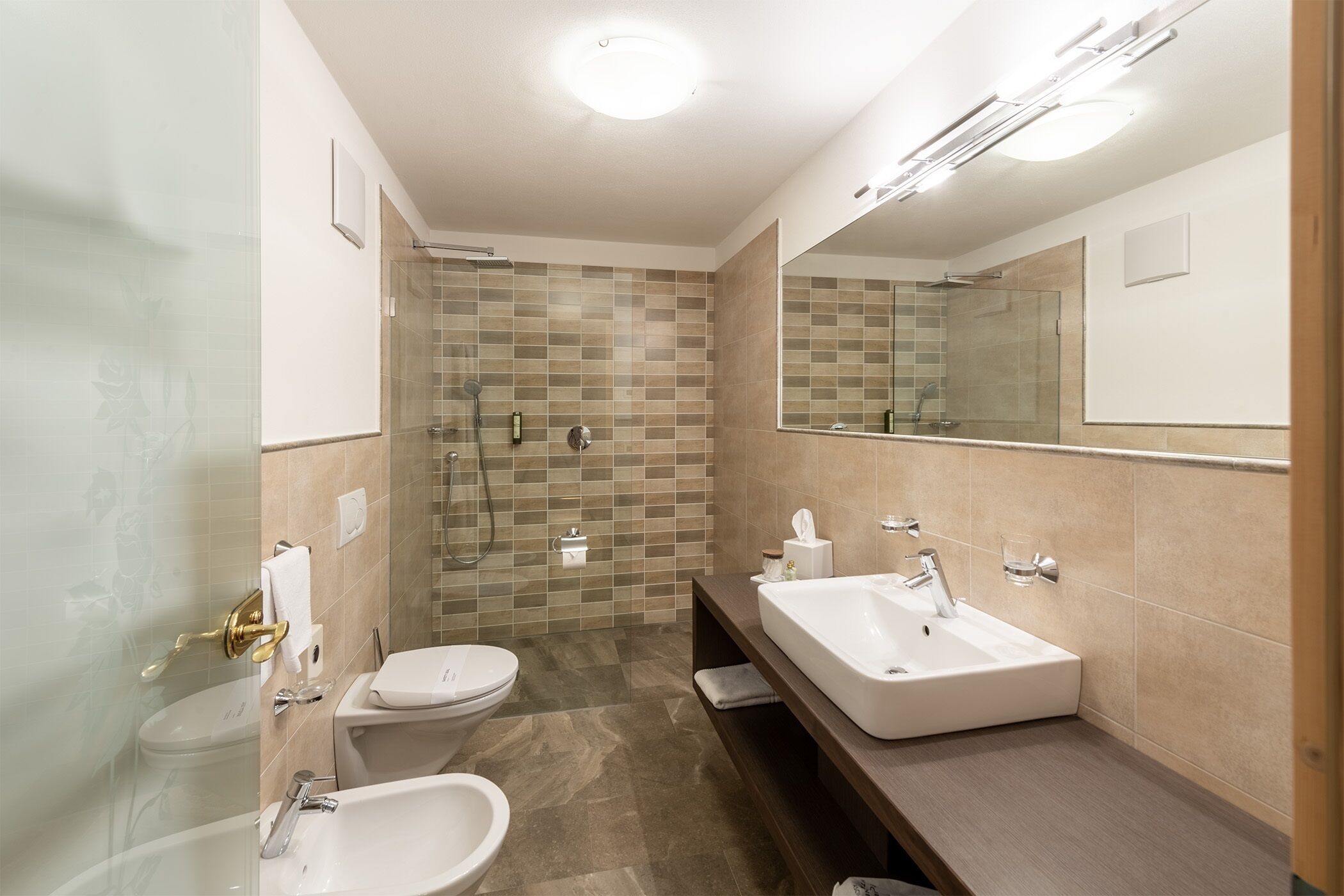 A modern bathroom with a glass shower enclosure, two sinks, and a large mirror.