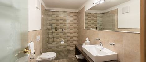 A modern bathroom with a glass shower enclosure, two sinks, and a large mirror.