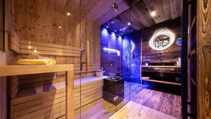 A sauna room with wooden walls, a bench, a glass-enclosed shower area, and a circular logo on the wall. - Hotel Arkadia - Adults Only (Corvara in Badia)