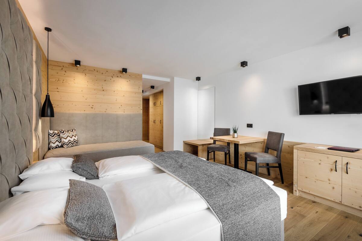 A modern hotel room with a large bed, a desk, and a TV mounted on the wall.