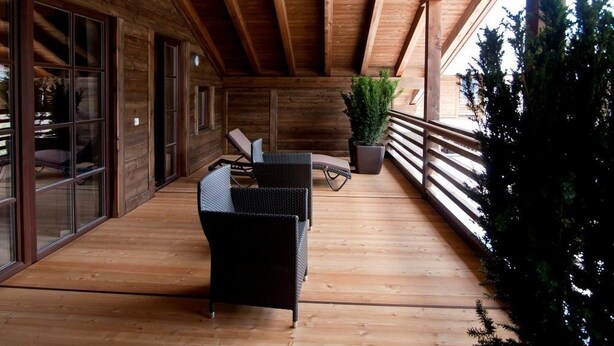 A covered wooden deck with wicker furniture and a potted plant. - Zin Senfter Residence (San Candido)