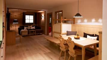 A cozy room with a wooden dining table, chairs, a sofa, and a TV.