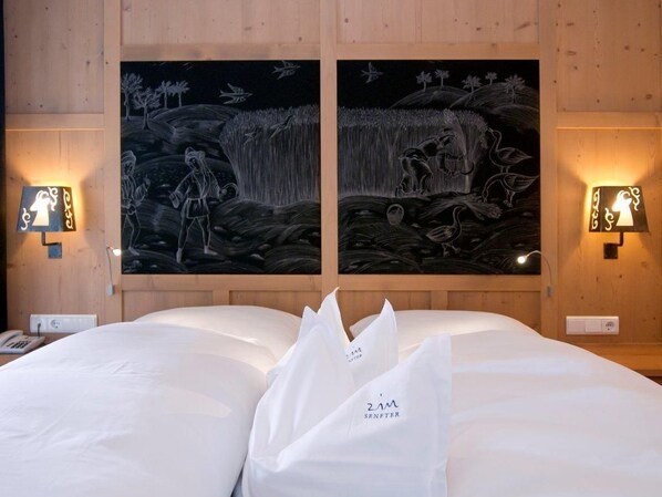 A hotel room with a bed, two wall-mounted light fixtures, and two large wall paintings. - Zin Senfter Residence (San Candido)