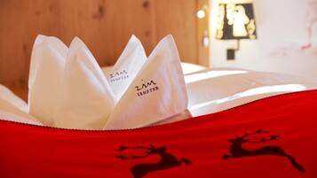 Una cama con una colcha roja que muestra siluetas de renos y un almohadón blanco con el texto 'ZIM SENFTER'.