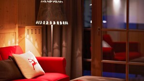 A cozy room with a red sofa, a small wooden table, and a lamp. - Zin Senfter Residence (San Candido)